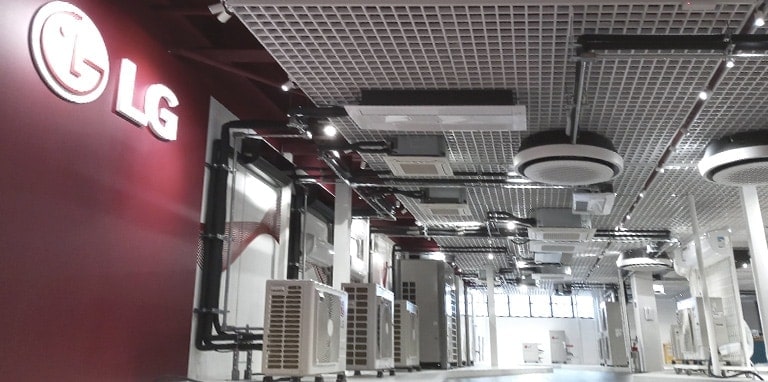 In a showroom-like space, a large LG logo graces the left wall while a series of LG indoor and outdoor units punctuate the ceiling and floor.