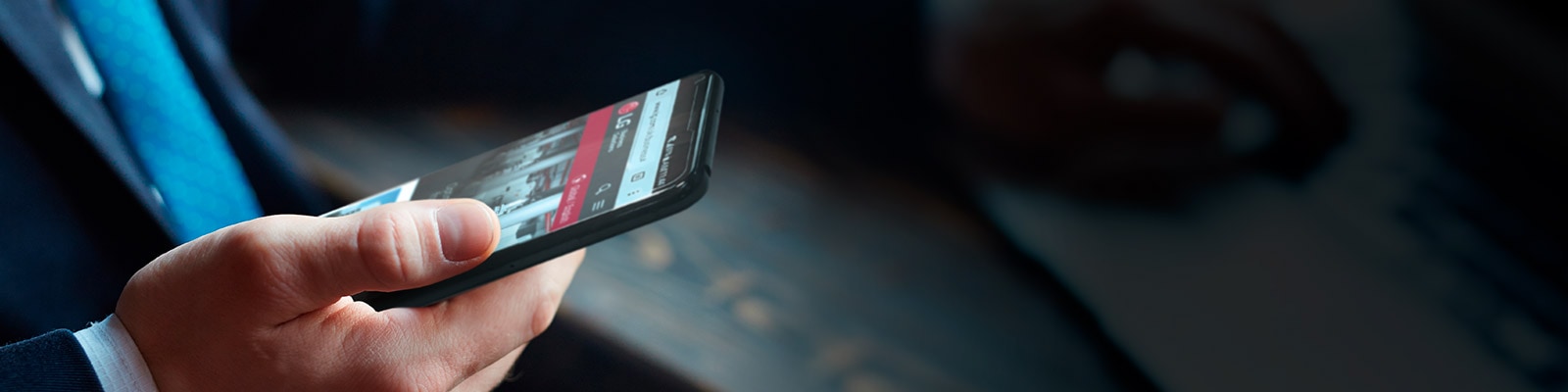 A man in a suit holds a smartphone in his right hand, displaying the LG website.