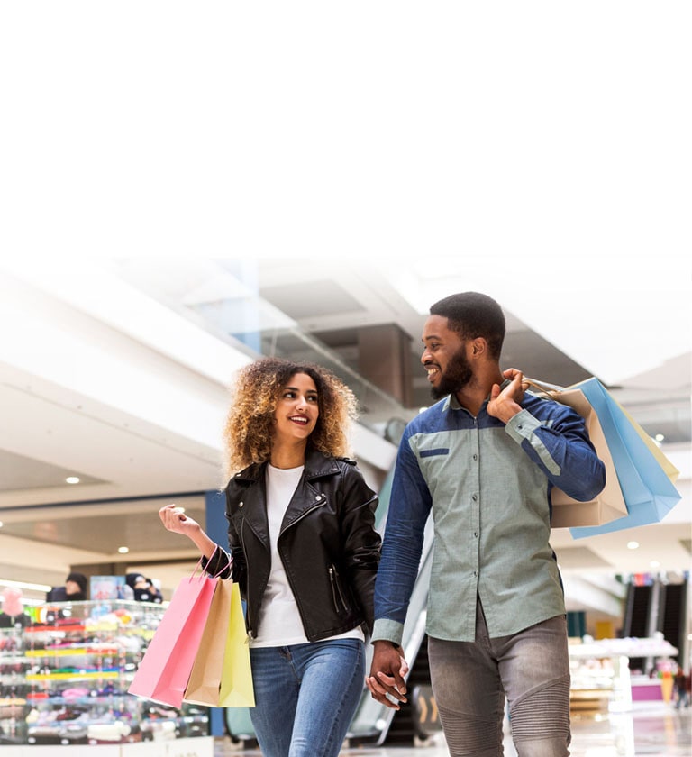 A couple shopping at a mall with colorful shopping bags.