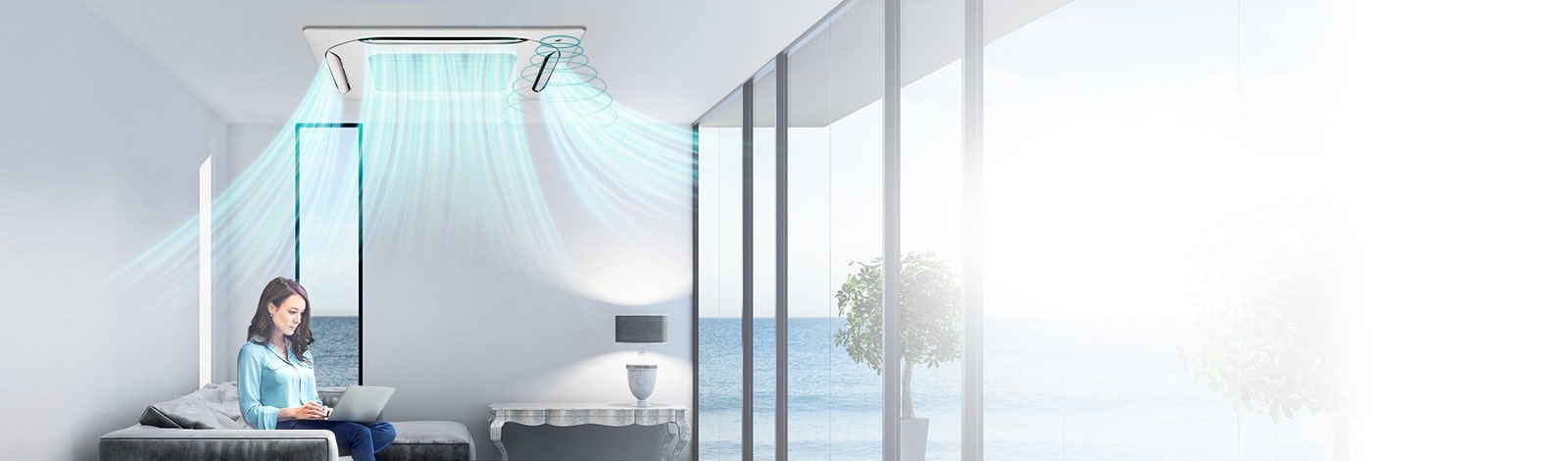 Image of a woman sitting on a sofa enjoying the wind of a 4 way cassette mounted on the ceiling.