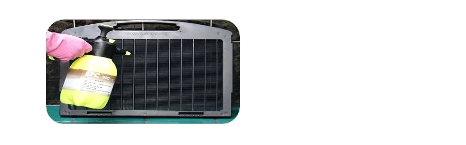 Garbed in gloves, a person expertly wields a weeding sprayer, applying water to a black, rectangular air purification filter.