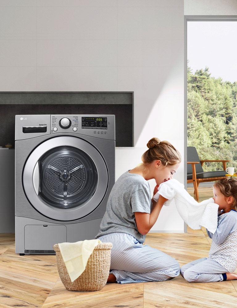 A mother and daughter sit on the floor holding and enjoying the smell of a towel that just came out of the Condensing Type Dryer that sits next to them.