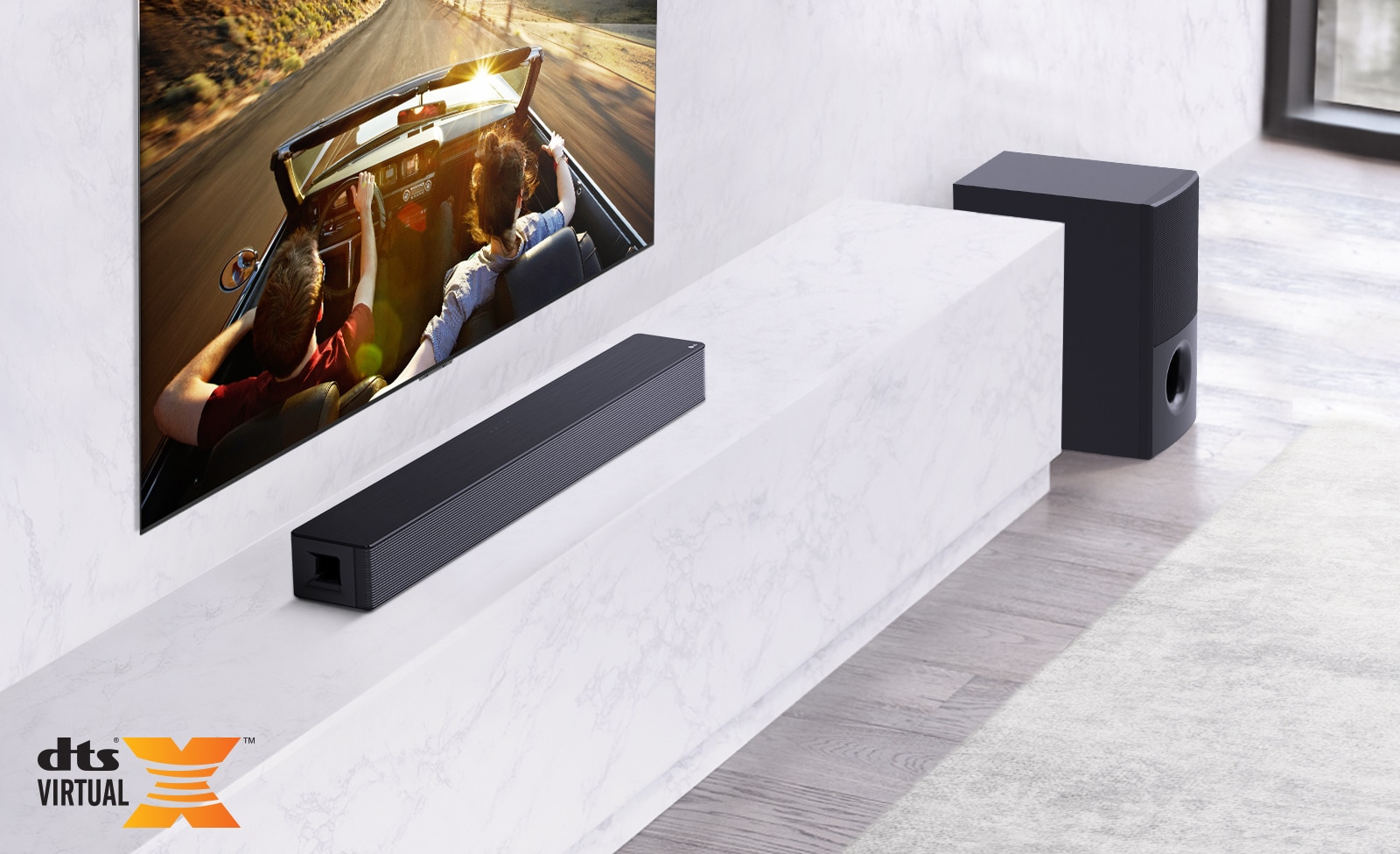 TV is on the wall, LG Soundbar is below on a white marble shelf with a sub-woofer to the right. TV shows a couple in a car. 