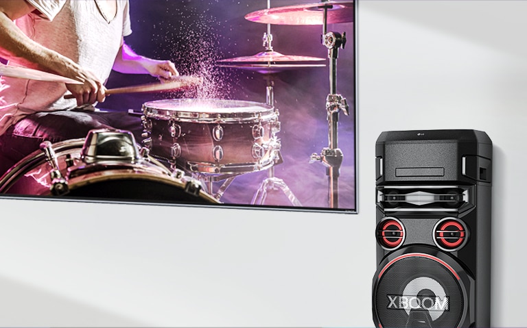 A TV is on a wall with an LG XBOOM to the right of it.