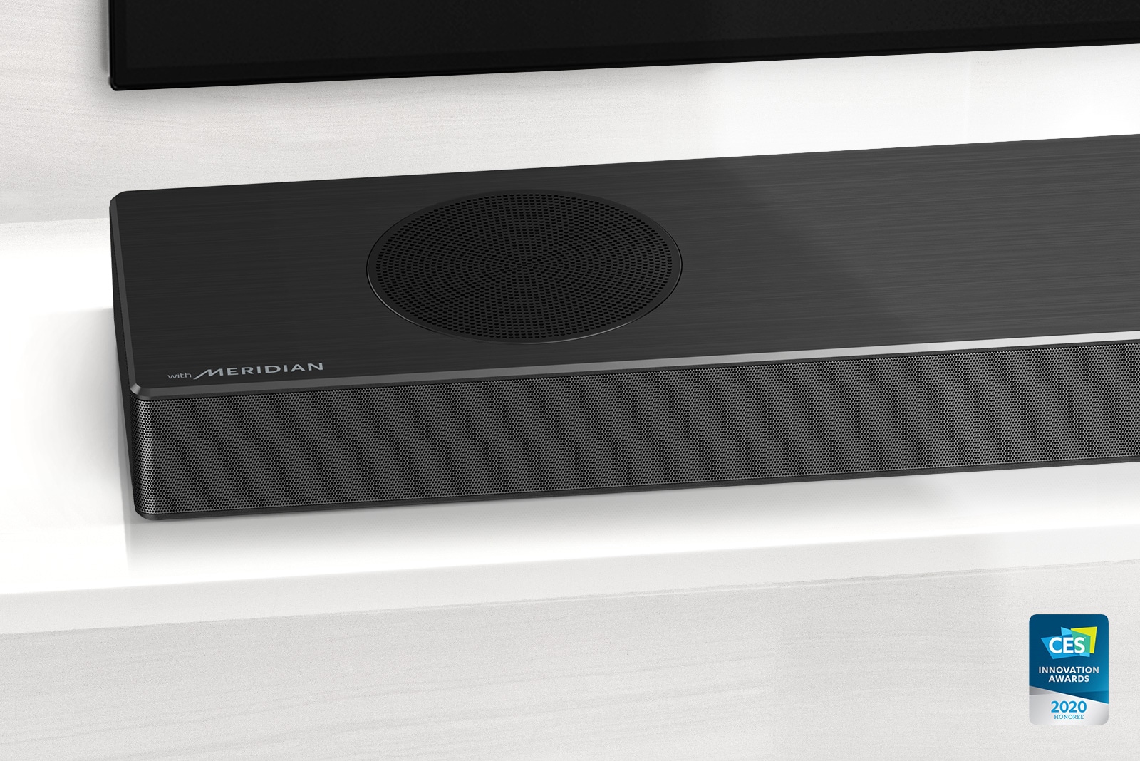 Close-up of LG Soundbar left side with Meridian logo shown on bottom left corner. Bottom left side of TV is also visible. 