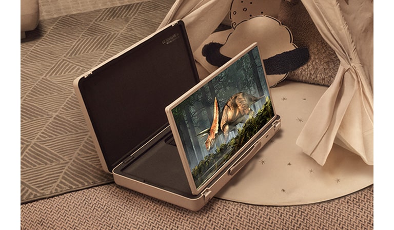 LG StanbyME Go case is opened up and the screen propped up. Two kids at home in a camping setup with a tent and warm, cozy lights. They are watching a video on the StanbyME Go screen.