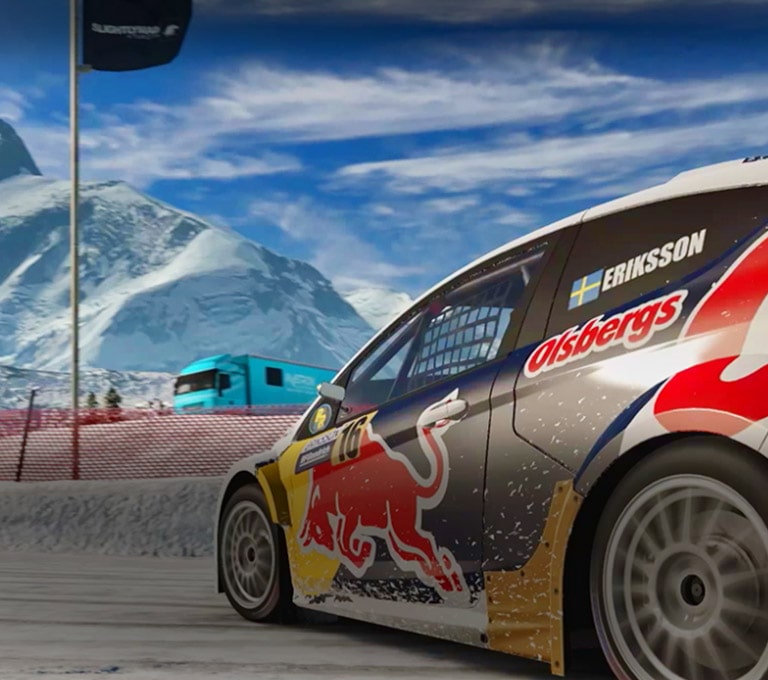 A scene from a racing game. A car is going round a corner of a snow covered circuit.