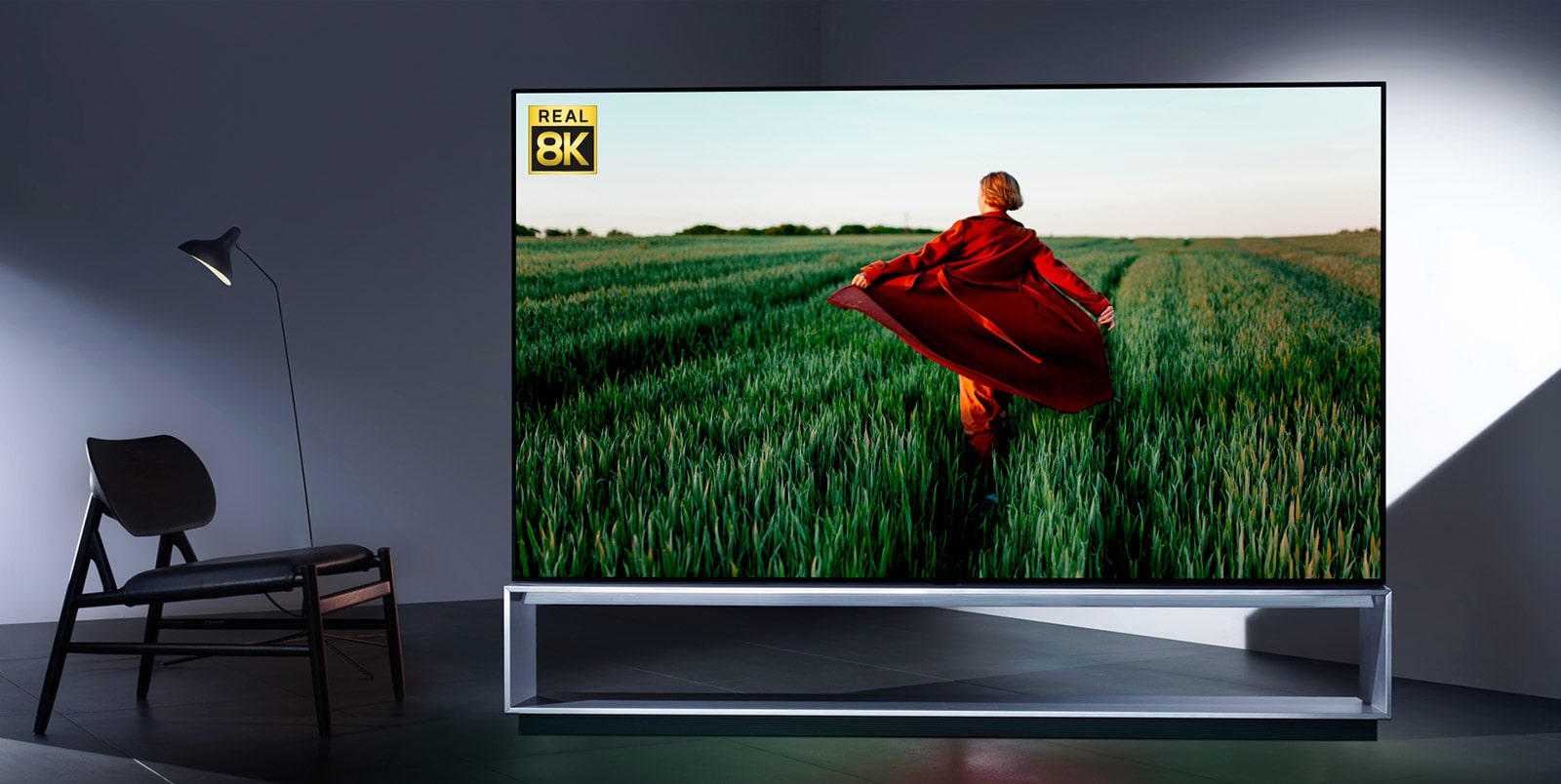 An LG OLED 8K TV, showing 8K realism via an image of a woman in a red trench coat running in a green rice field
