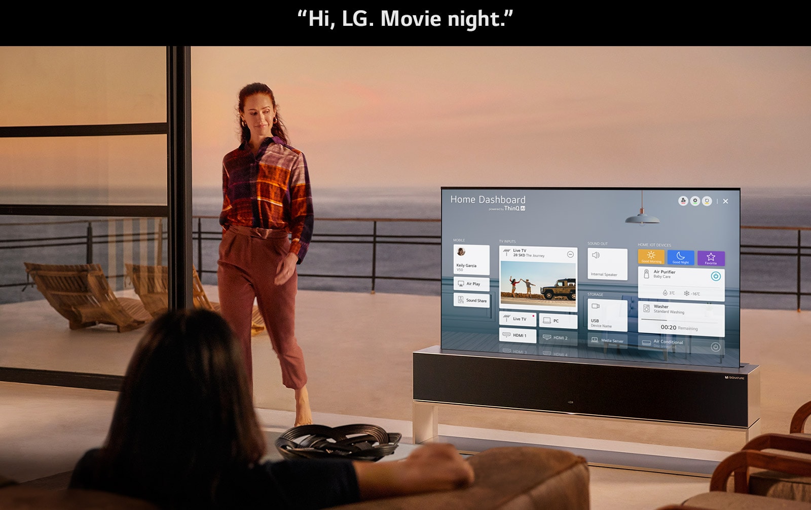 A woman is setting an optimized set for cinema via Home Dashboard on TV in the living room with an ocean-front terrace