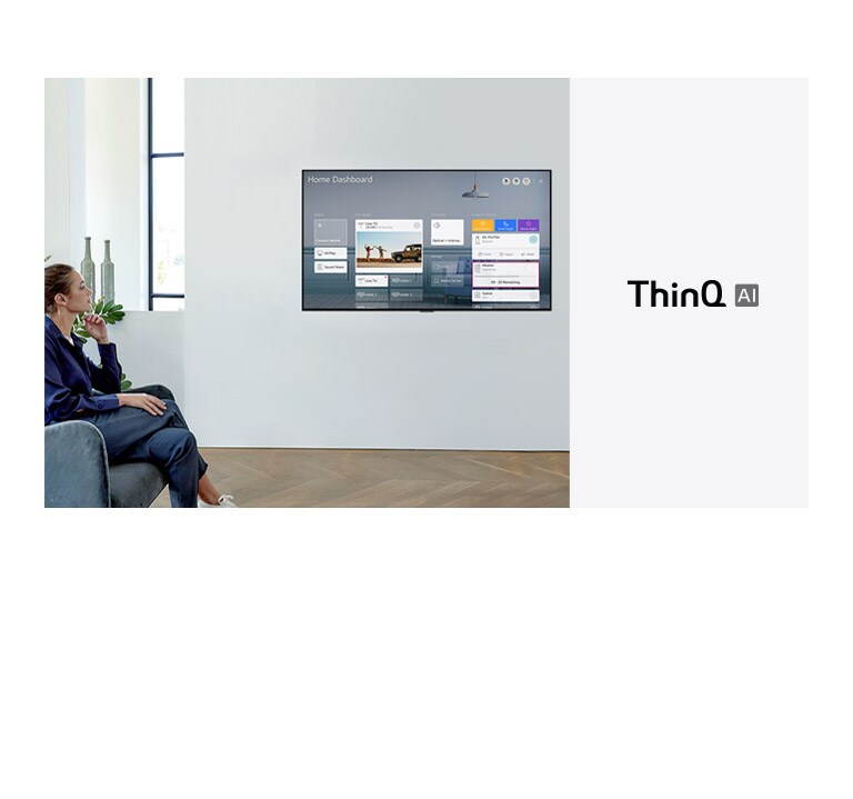Woman sitting on a chair in the living room with the Home Dashboard on the TV screen