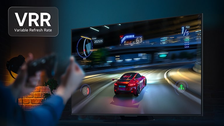 Hands holding a game controller in front of a TV with a car racing game on the screen. VRR, variable refresh rate logo is visible. 