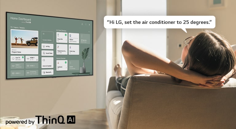 Woman lying on a sofa telling TV to lower the temperature with Home Dashboard on the TV screen.