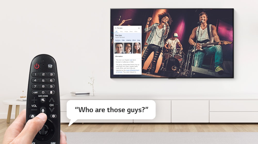 Closeup of hand controlling TV with a remote control to ask who the guys singing on the TV are.