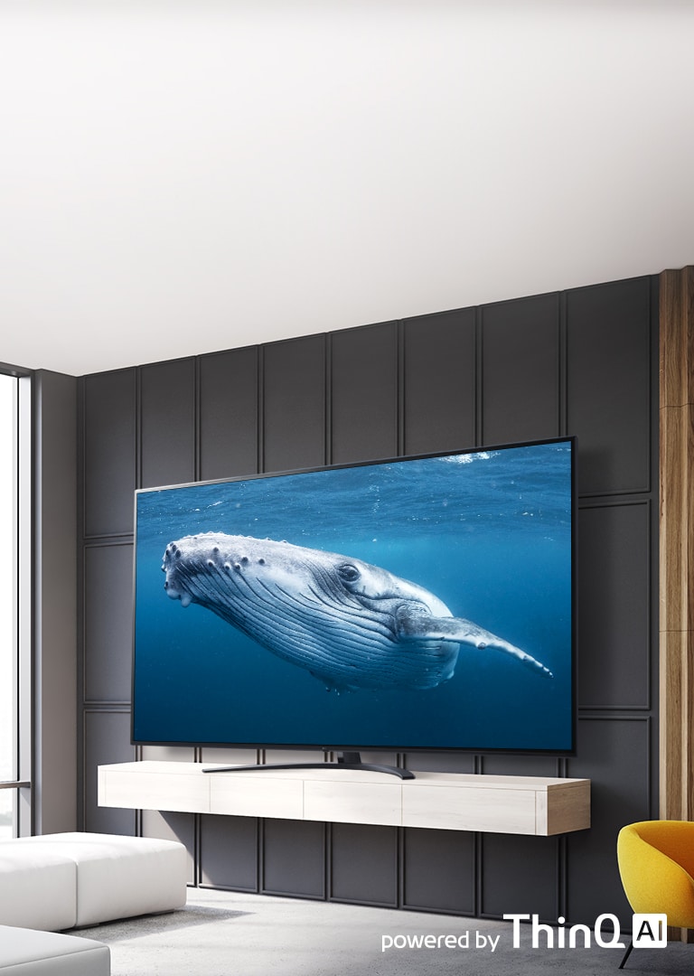 In a living room, there is a large screen TV displaying an image of a big whale in the sea. On the image, there is an introduction of a large screen TV on the left center and a powered by ThinQ AI logo on the upper right.