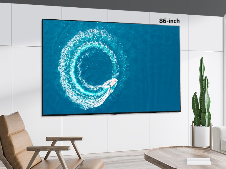 A comparison between 55 inch screen and 86 inch screen which were both hung on the wall displaying a boat making a wave in the middle of sea.