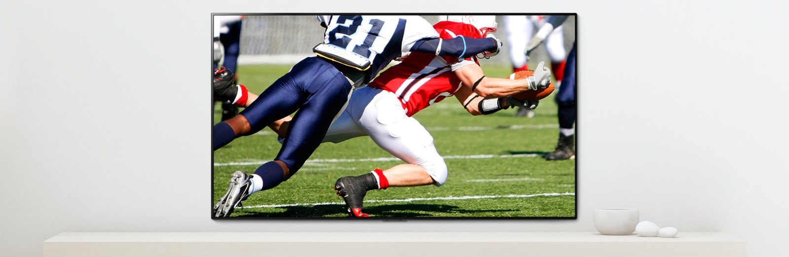 A scene of a sports game showing two men who are playing dynamically playing American football on a TV screen