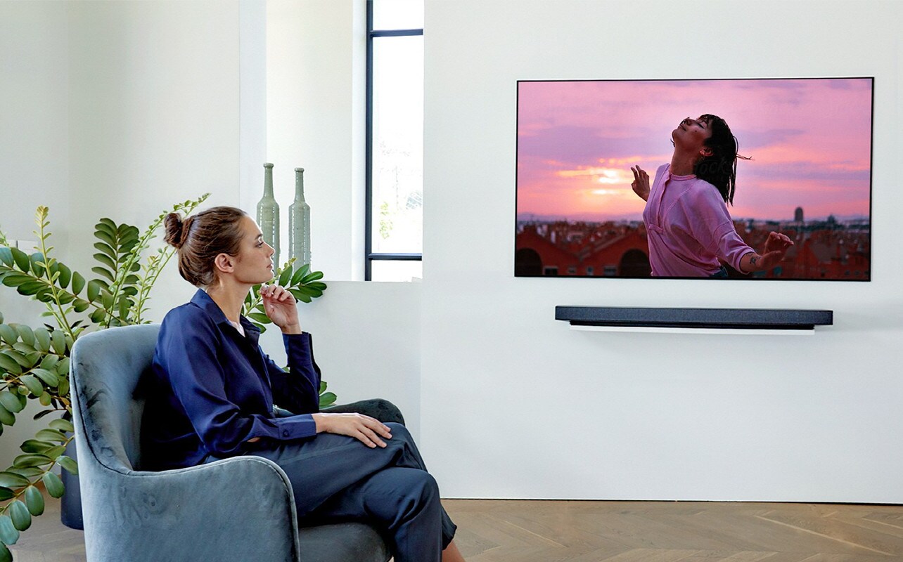 a woman watching TV on the single couch
