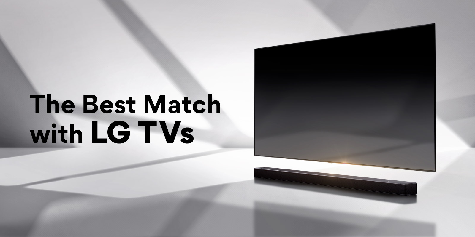 Barre de son et téléviseur posés sur un sol blanc, une ombre se projetant depuis l’extérieur, juste derrière.