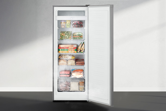 Intérieur d'un congélateur vertical, porte ouverte, montrant plusieurs étagères et compartiments remplis d'aliments surgelés variés