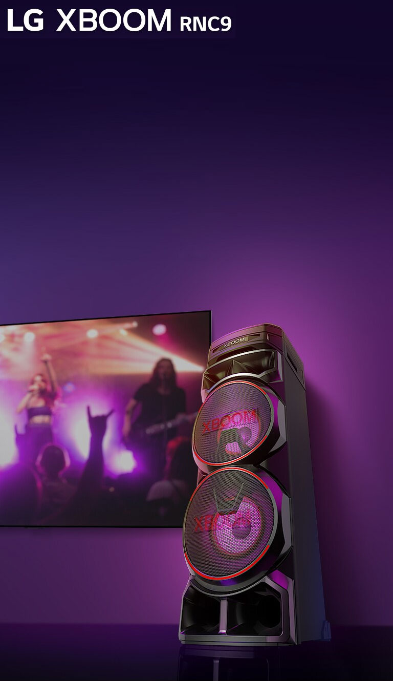 Vue en contreplongée du côté droit de l’enceinte LG XBOOM RNC9 sur fond violet. L’éclairage du XBOOM est également violet. Et un écran de télévision diffuse un concert.