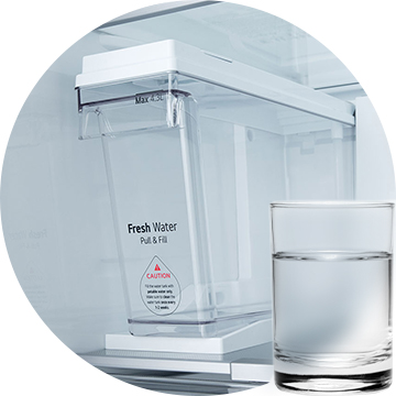 Gros plan sur l’appareil à glaçons sans plomberie LG 2007 avec réservoir d’eau Pull & Fill et un verre d’eau placé à l’avant.
