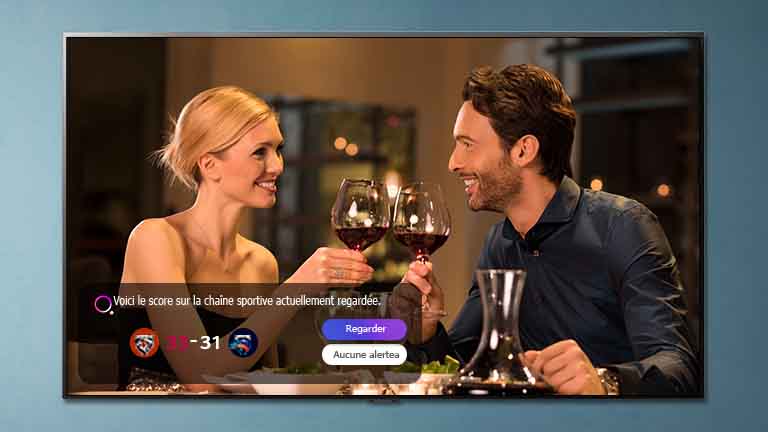 Um homem e uma mulher brindam em uma tela de TV como um alerta esportivo aparece