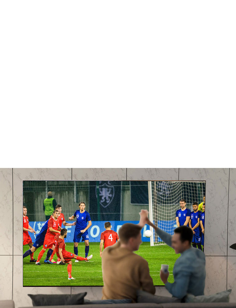 Des personnes regardent un jeu de sport à la télévision dans le salon avec un téléviseur à très grand écran