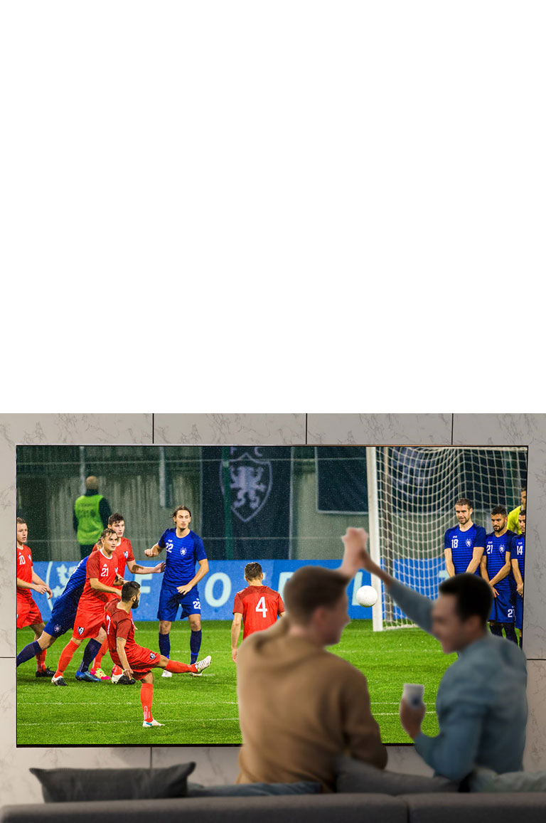 Des personnes regardent un jeu de sport à la télévision dans le salon avec un téléviseur à très grand écran