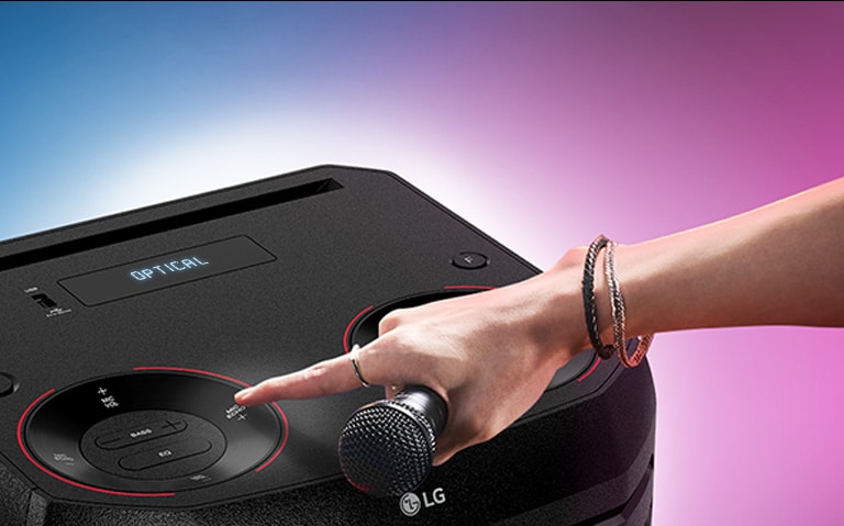 Une main tenant un micro appuie sur le bouton écho situé sur le dessus de l’enceinte LG XBOOM.