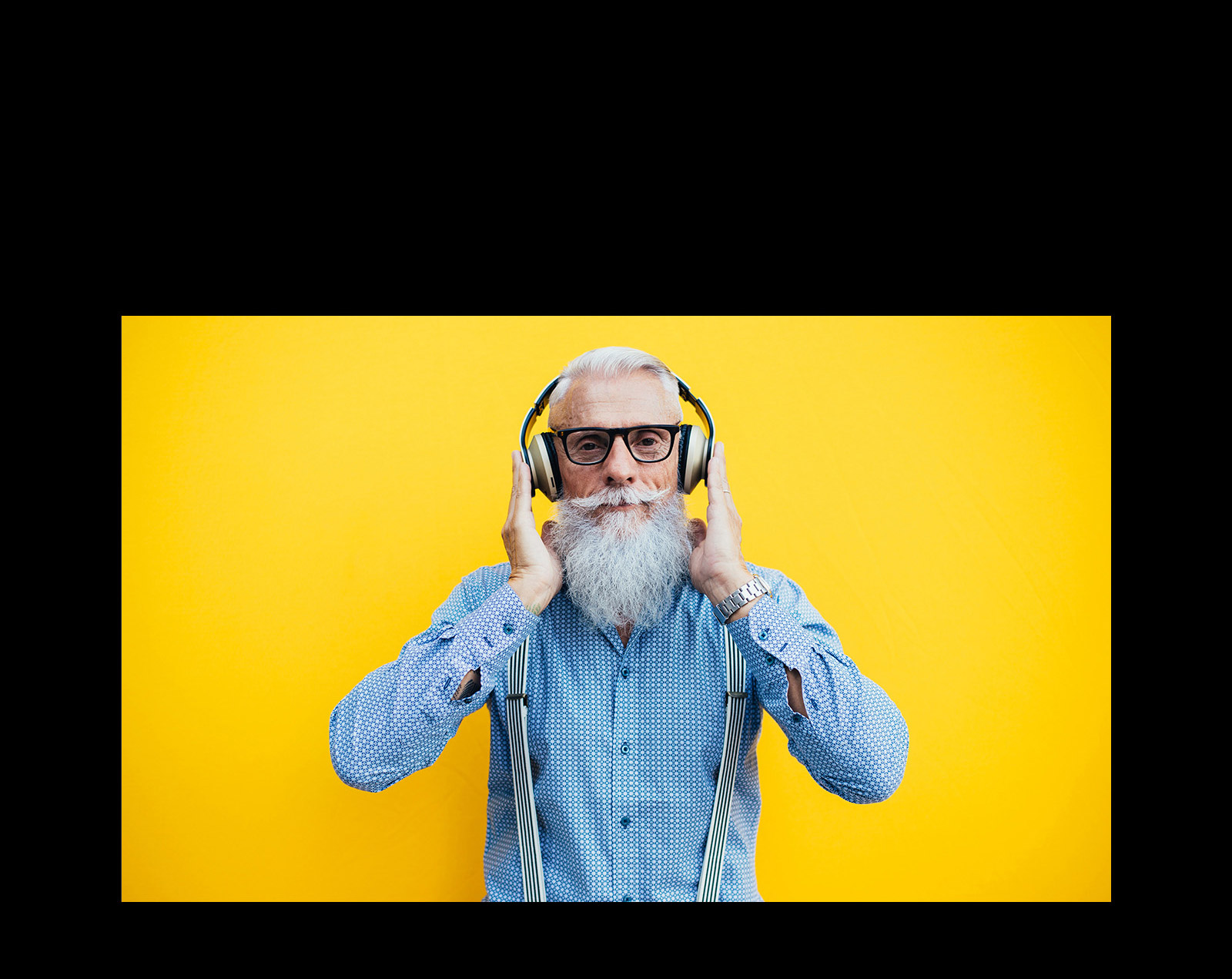 Un grand-père se tient devant un mur jaune – portant un casque.