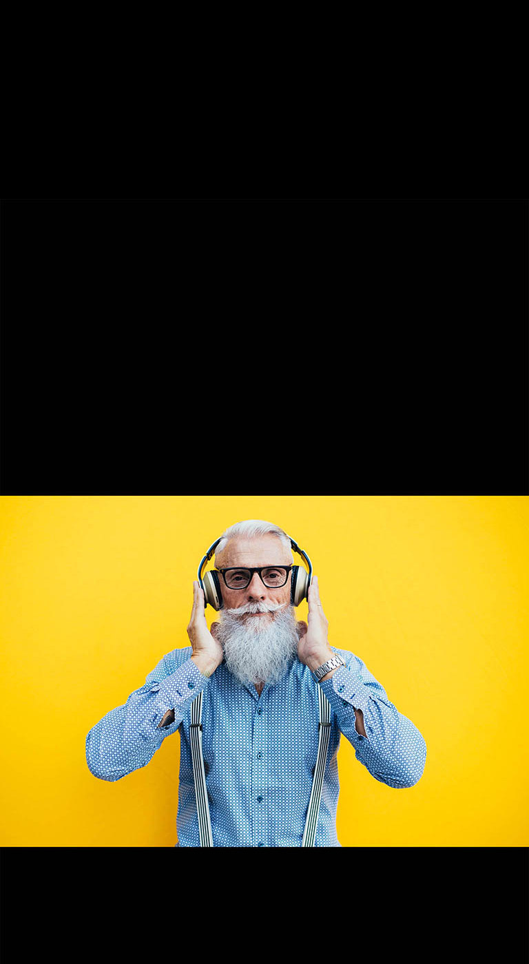 Un grand-père se tient devant un mur jaune – portant un casque.