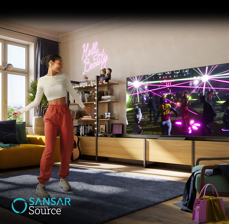 Une femme danse dans son salon tout en regardant un concert dans le metaverse de Sansar sur l’écran du téléviseur.