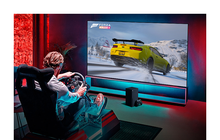 Un homme joue à un jeu de course sur le téléviseur LG OLED et la Xbox series X.