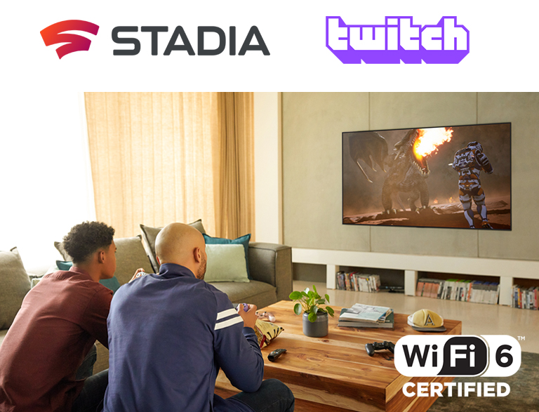 Le logo de Google Stadia et de Twitch sont alignés. Deux hommes sont assis sur un canapé et jouent à un jeu avec des manettes et le Wi-Fi 6 certifié dans un salon.