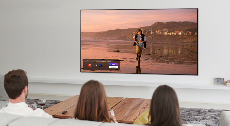 Trois personnes en train de regarder un écran de téléviseur montrant une scène d’un film fantastique avec une Sports Alert