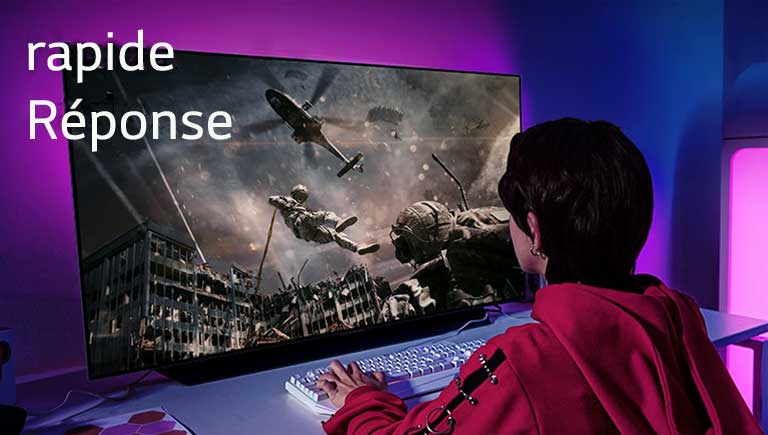 Une fille jouant à un jeu d’ordinateur avec un téléviseur grand écran affichant un soldat descendant d’un hélicoptère.