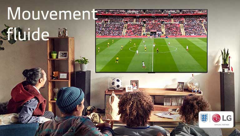 Quatre personnes assises sur un canapé regardent un match de football dans un salon.