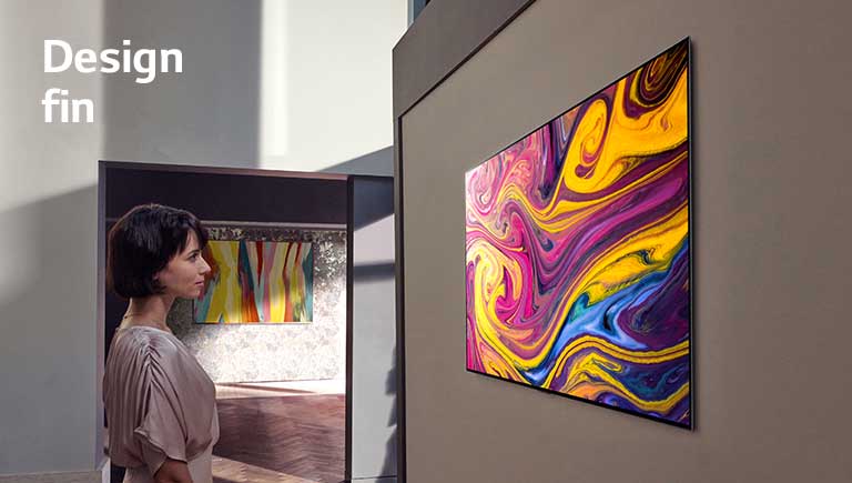 Une femme regarde un téléviseur fixé sur le mur qui affiche une œuvre d’art.
