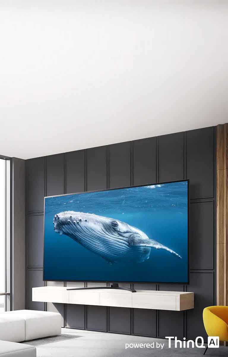 Dans un salon, il y a un grand écran de téléviseur qui affiche l’image d’une baleine dans la mer. Sur l'image, on peut voir un téléviseur grand écran au centre gauche et un logo « Fonctionnant avec ThinQ AI » en haut à droite.