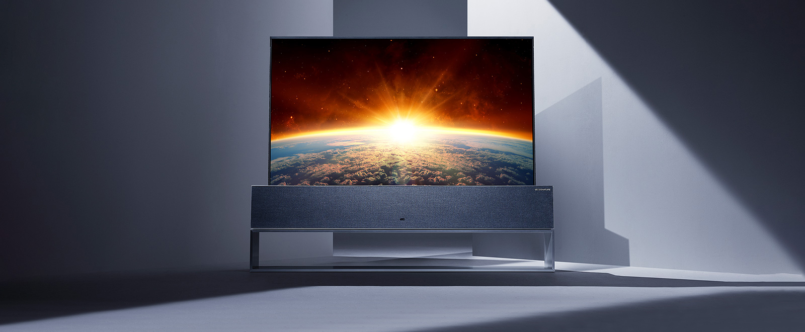 Une image de LG SIGNATURE Rollable TV en pleine vue placée au centre d'un espace de couleur grise.