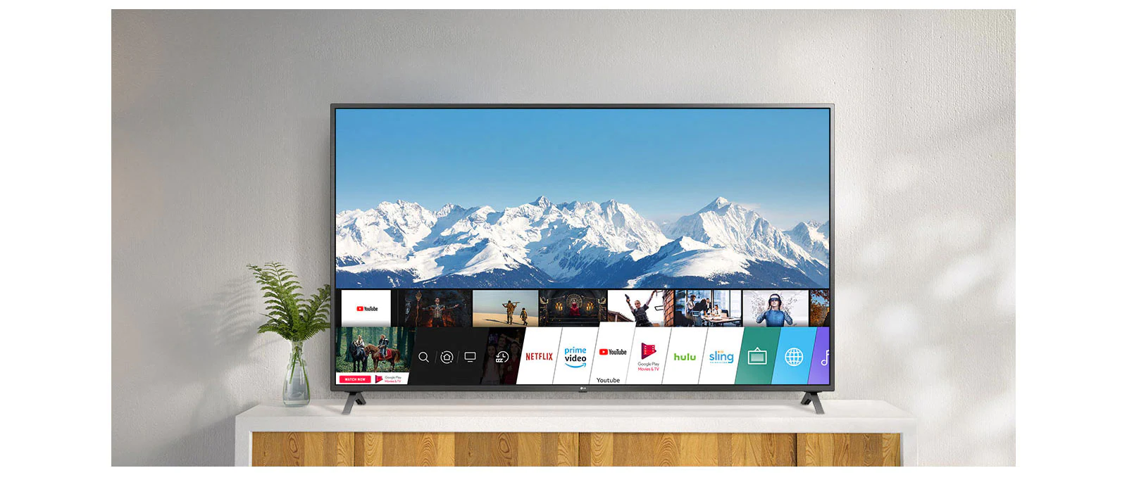 Téléviseur placé sur un support blanc contre un mur blanc. Écran de téléviseur montrant un écran d’accueil exécutant webOS.