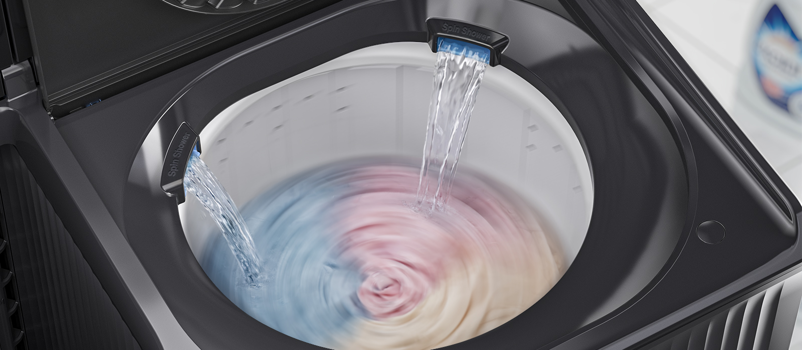 Une cuve de machine à laver à chargement par le haut avec deux jets d’eau coulant sur les vêtements, illustrant une douche à double rotation pour un rinçage uniforme.