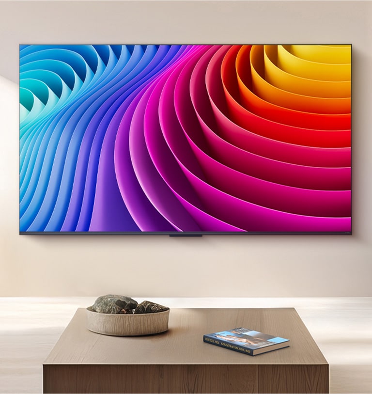 LG QNED TV montada en la pared de una bella y lujosa sala de estar. En la TV hay una imagen abstracta con un degradado de diferentes tonos que ilustra la manera en que Dynamic QNED Color Pro puede ofrecer un amplio rango de colores.