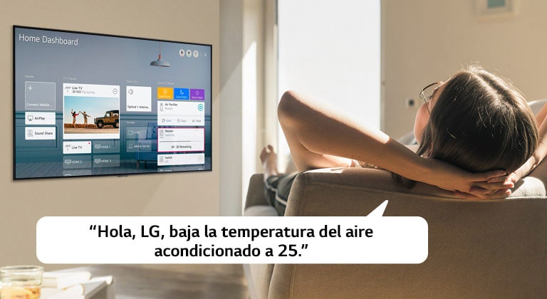 Mujer recostada en un sofá diciéndole a la TV que baje la temperatura con el Panel de inicio en la pantalla de la TV