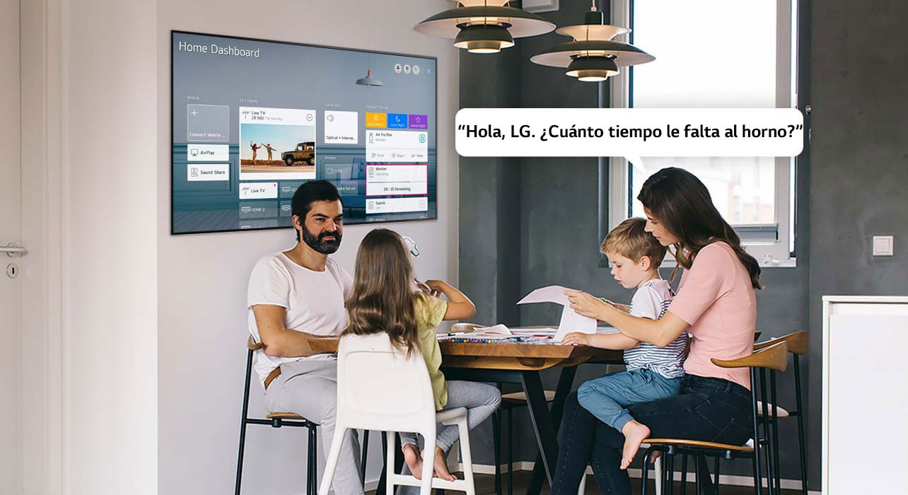 Familia sentada en una mesa con la madre preguntándole a la TV el tiempo restante del horno