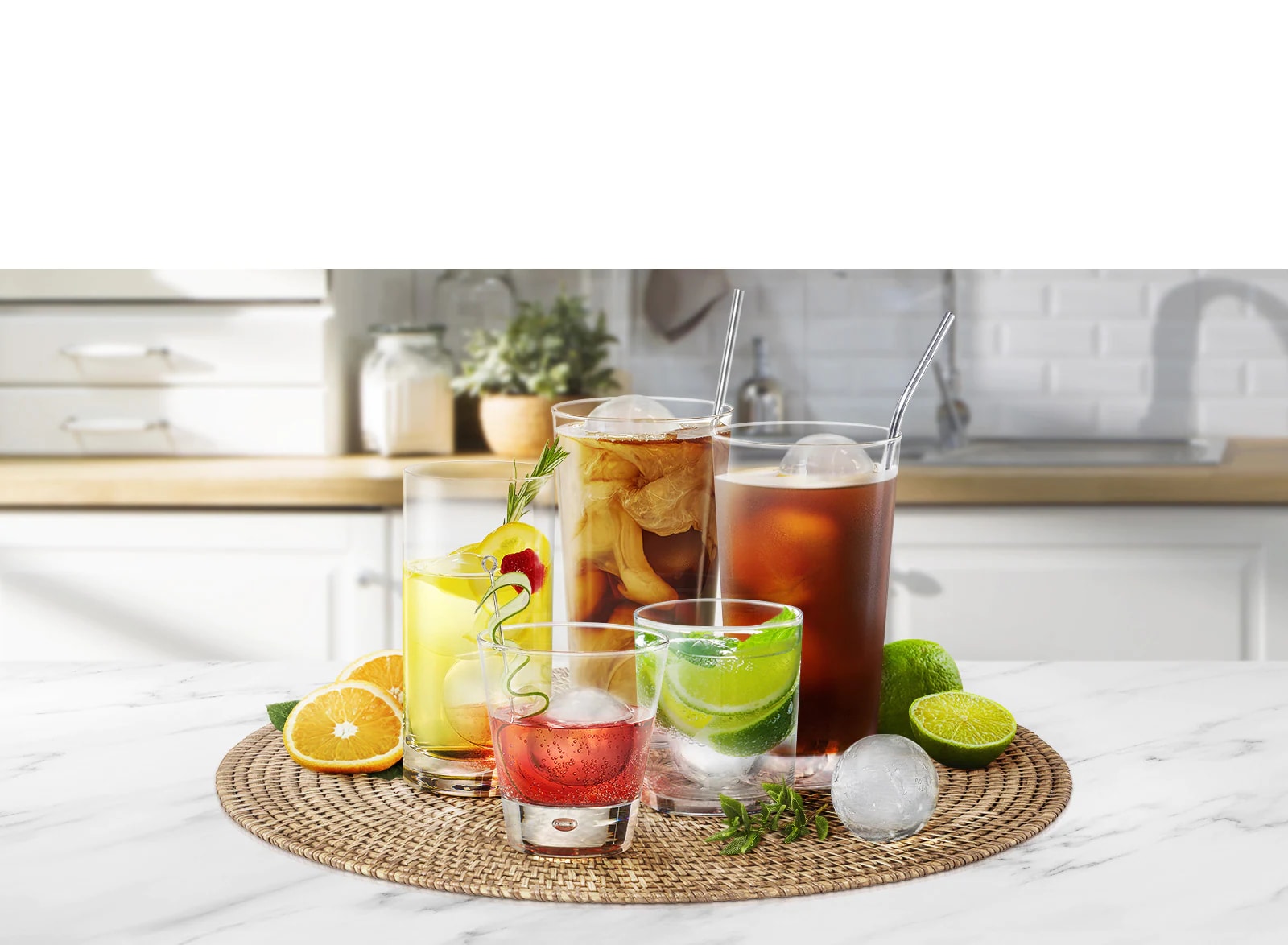 Varios vasos de distintos tamaños que contienen diferentes bebidas con cubitos de hielo redondos están sobre una encimera de cocina.