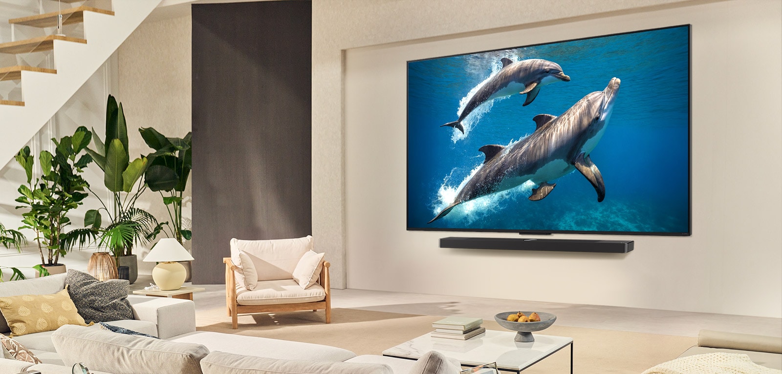 Una familia sentada en el sillón frente a una LG QNED TV montada en la pared; una pequeña niña señala la pantalla que muestra dos delfines. 