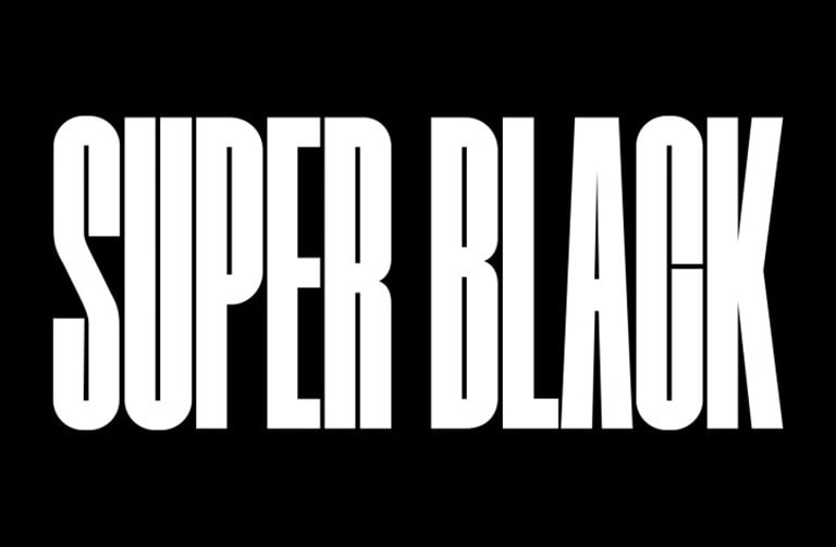 Las palabras “NEGRO PERFECTO” aparecen en mayúscula negra en negrita. Una escena montañosa oscura con definición clara luego surge para cubrir las letras, para revelar también una aldea y dunas de arena. La copia negra desaparece detrás de un cielo oscuro.