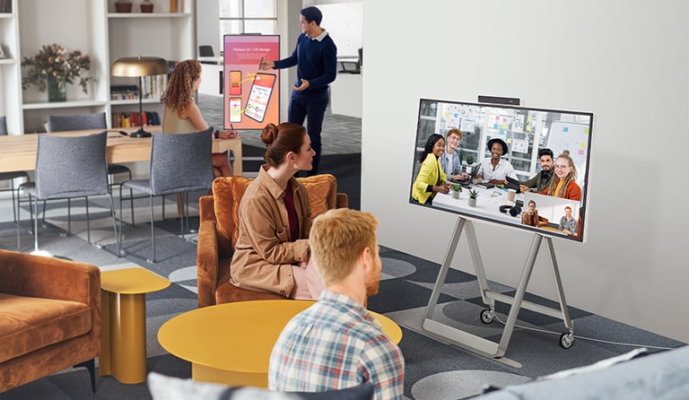 Dos personas están en una videoconferencia usando One:Quick Flex en un espacio con un ambiente informal. En otra mesa que se encuentra atrás, otras dos personas están haciendo una videoconferencia mientras voltean One:Quick Flex verticalmente y hacen marcas o escriben en la pantalla con un lápiz táctil.