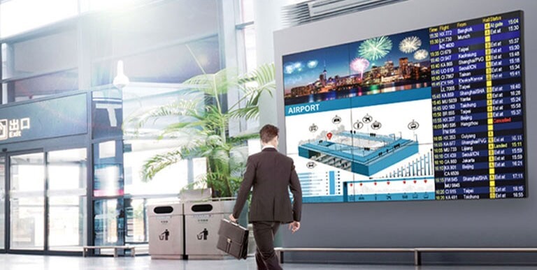  Un hombre pasa mientras mira la pantalla y la pantalla muestra colores vivos desde cualquier ángulo.